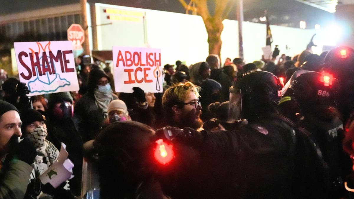 Police in riot gear confront protesters outside an ICE facility during a nighttime protest in Portland, Oregon.