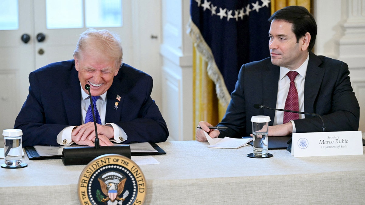 President Donald Trump laughs as Secretary of State Marco Rubio looks on during a White House meeting with energy industry executives.