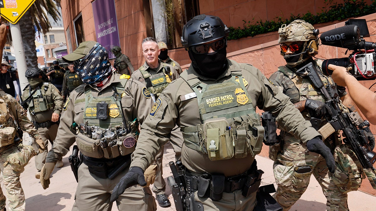A uniformed federal official walks at the front of a group of law enforcement officers in downtown Los Angeles.