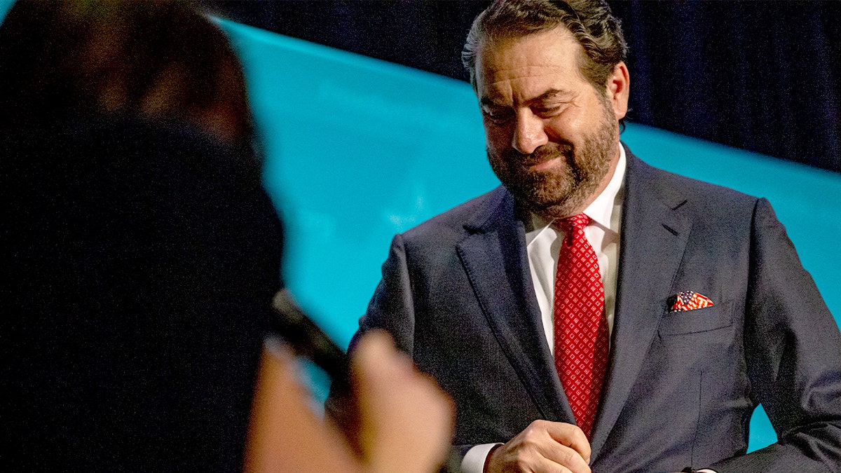 A Republican candidate rises from his chair to address a question during a televised primary debate.