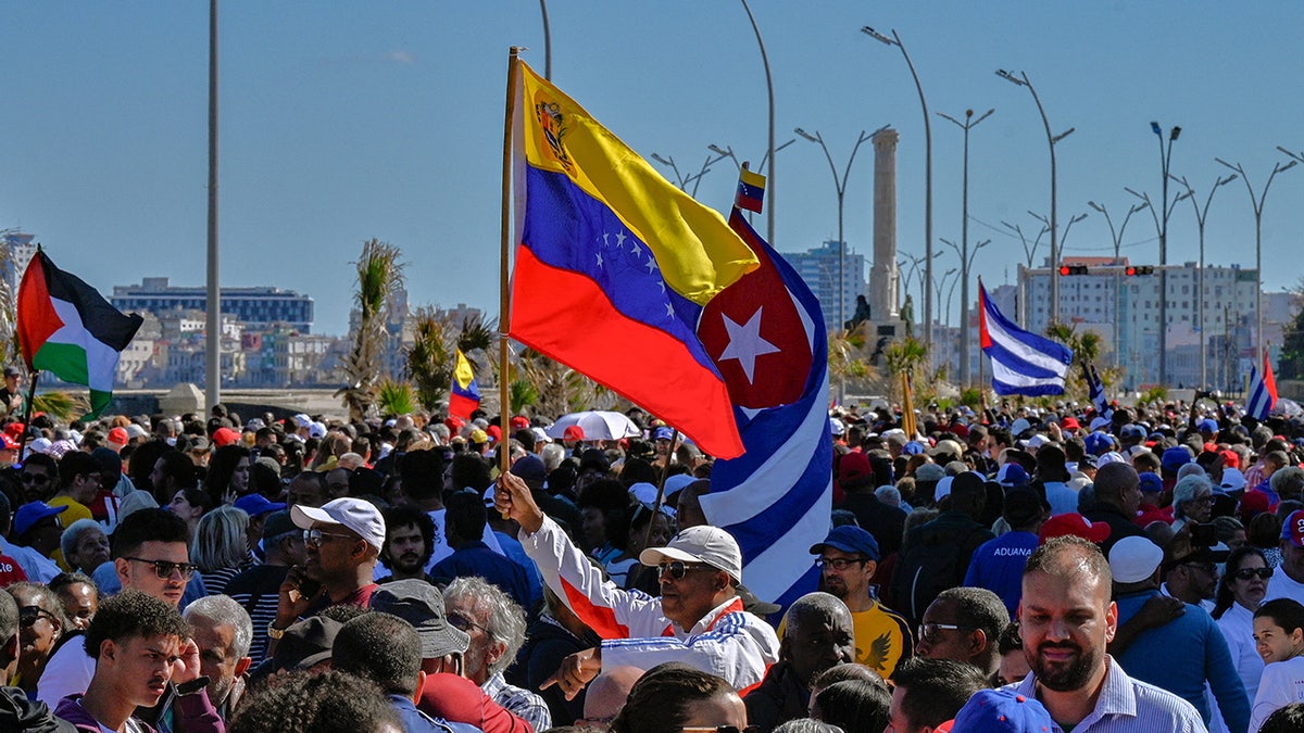 Man holds a Venezuelan flag and a Cuban flag