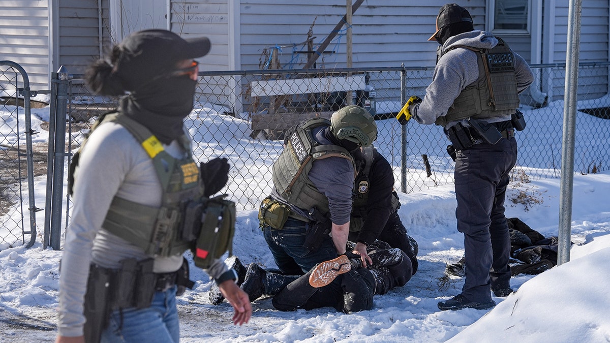 Individual lies on ground while being arrested by federal agents in Minneapolis