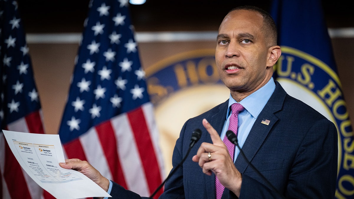Hakeem Jeffries holds up a piece of paper during a press conference