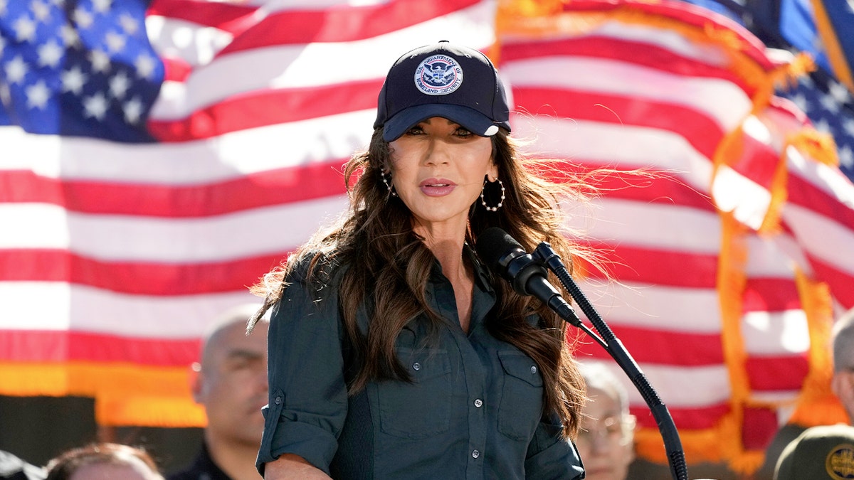 Kristi Noem stands in front of American flags