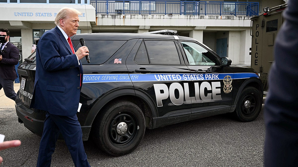 Donald Trump speaks by a cop car