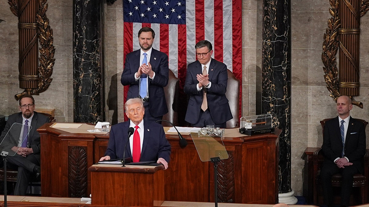 Donald Trump standing at a podium and speaking during the State of the Union address in the House chamber.