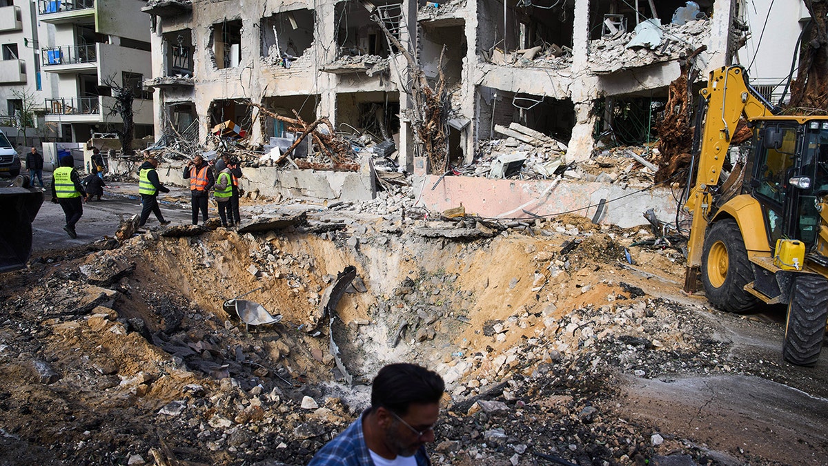 Rescue workers and military personnel surveying a site with significant structural damage and debris.