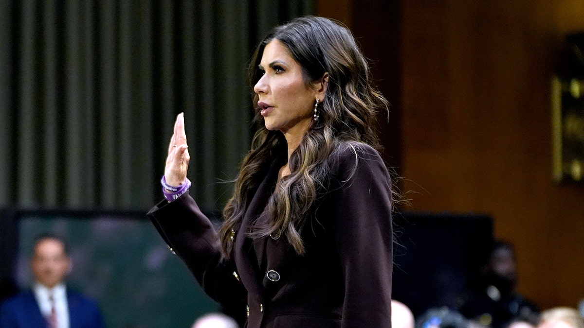 Department of Homeland Security Secretary Kristi Noem raising her right hand while being sworn in at a Senate hearing.
