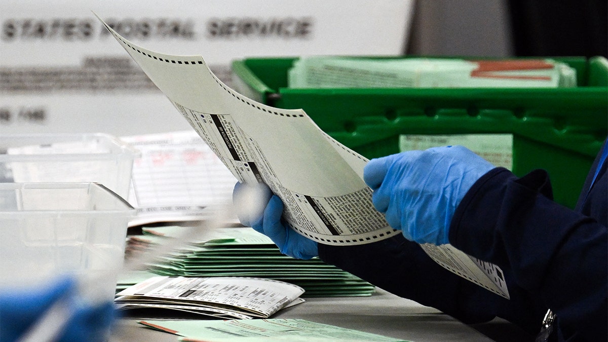 An election worker removes a ballot from an envelope to count and inspect the pages inside the Maricopa County Tabulation and Election Center (MCTEC) on Election Day, Nov. 5, 2024 in Phoenix, Arizona.
