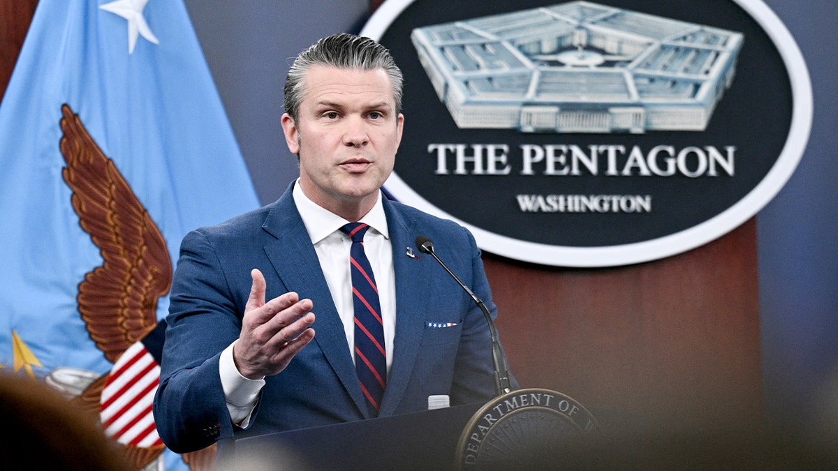 War Secretary Pete Hegseth addresses reporters at a Pentagon briefing room podium.