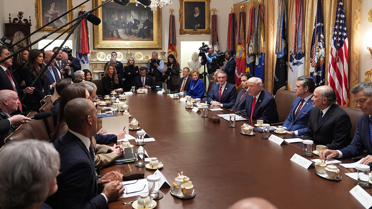 Donald Trump speaking while seated at a large table during a meeting.