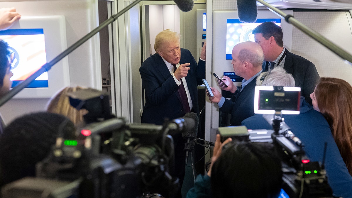 President Donald Trump answers questions from reporters inside Air Force One during a flight to Maryland.