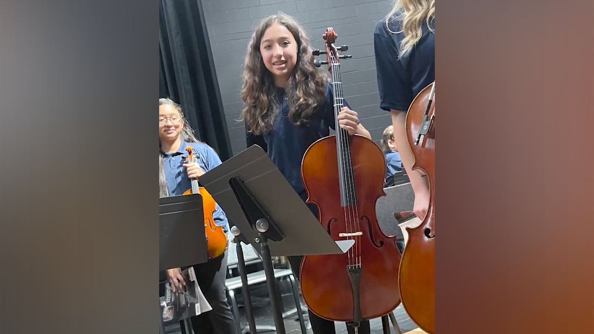 Jocelyn Nungaray holding a musical instrument and smiling