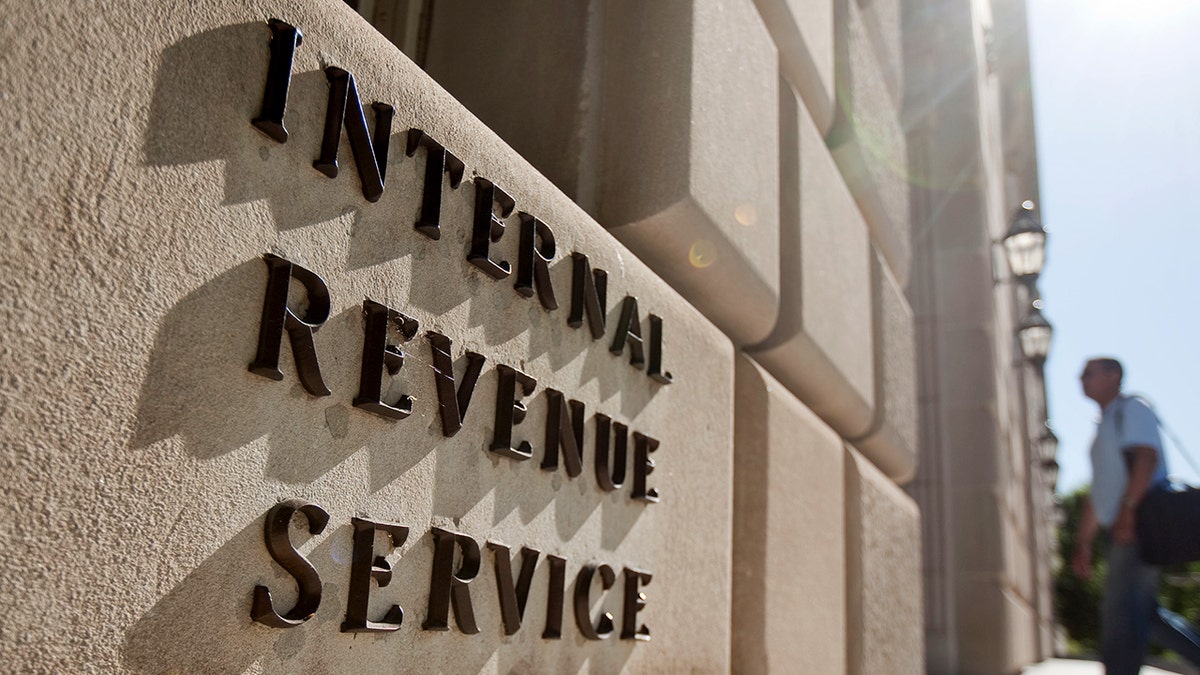 A man walking into a building with Internal Revenue Service lettering on the facade