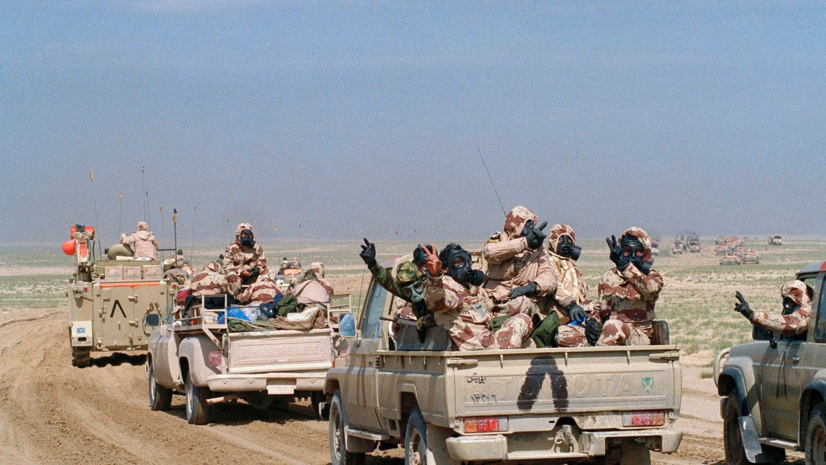 Kuwaiti troops wearing gas masks and protective suits riding in an armed motor convoy