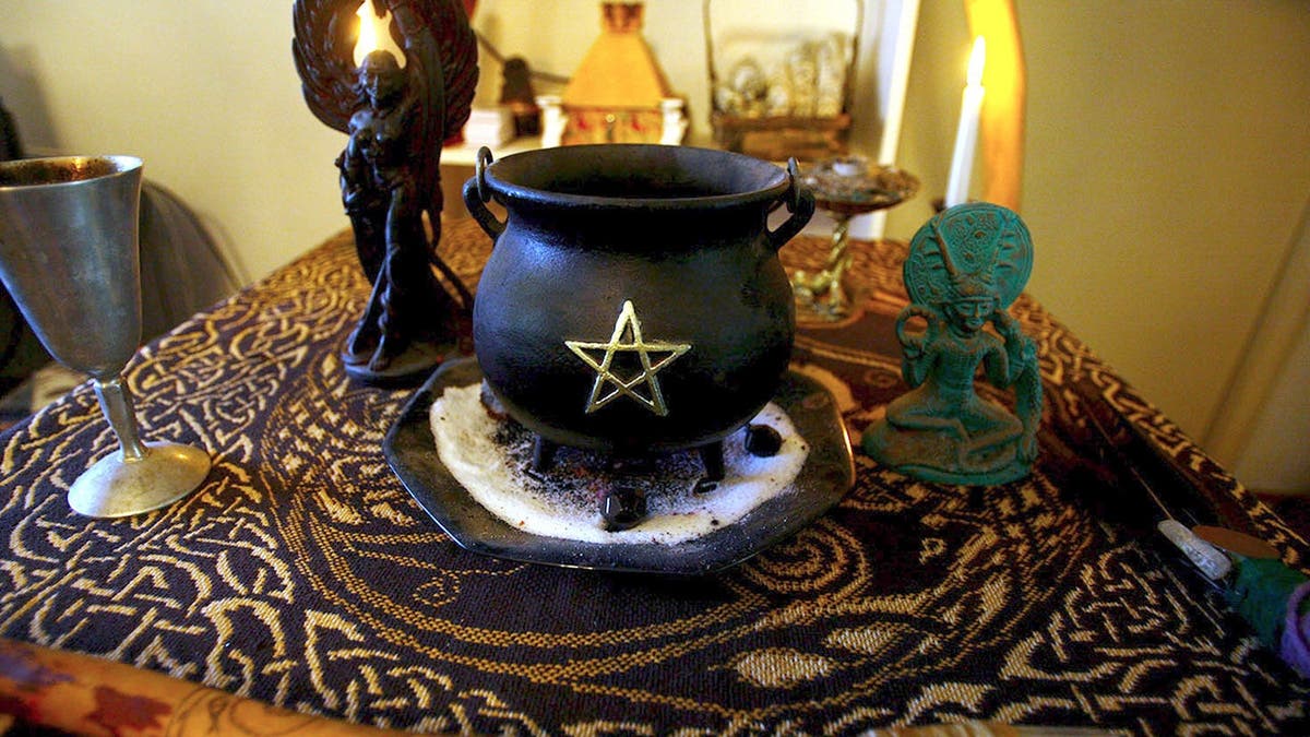 Rudy Alderette's altar featuring a cauldron with a pentagram, a wand, a chalice, and Wiccan statues.