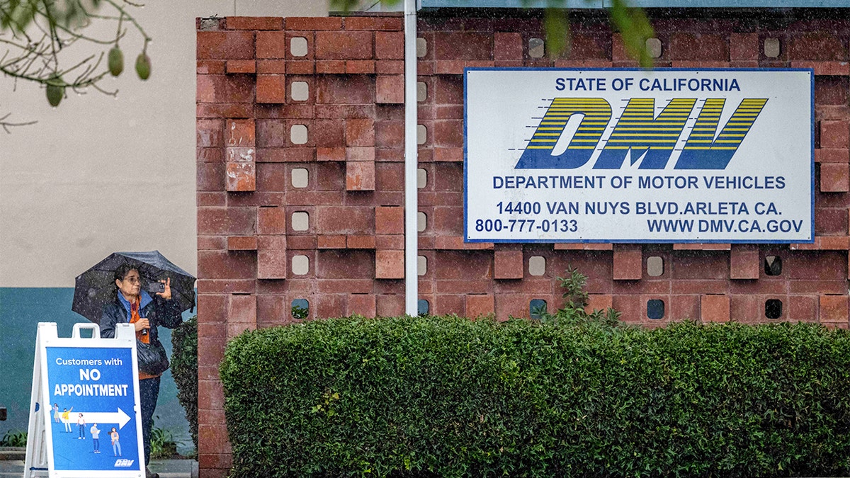 People walking through rain outside Arleta DMV office in California