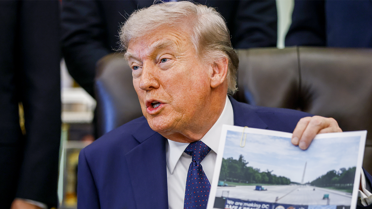 Trump holding up a photo of the progress on the National Mall's reflecting pool