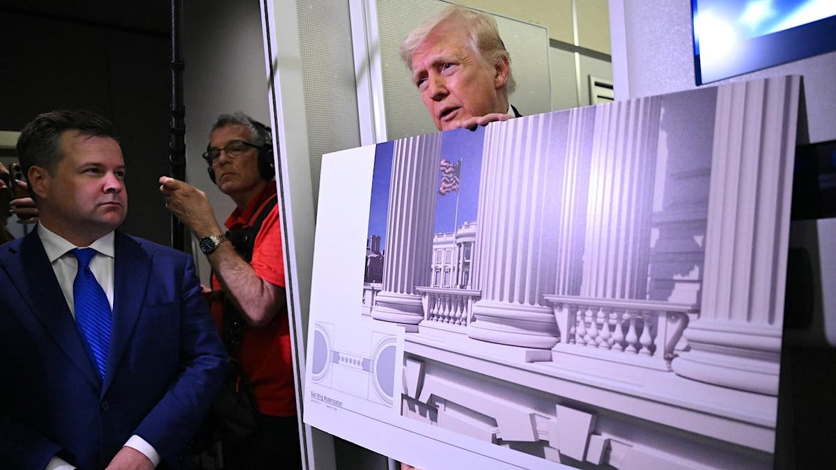 President Donald Trump holding a rendering while speaking to reporters aboard Air Force One
