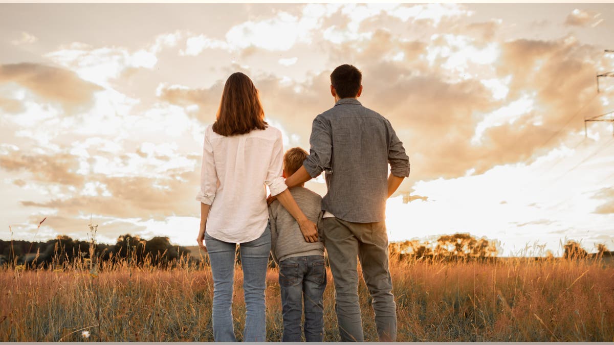 A family standing together watching the sun set.
