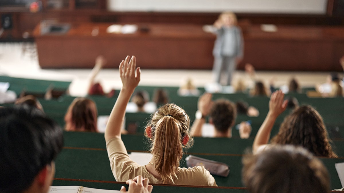 Woman raising her hand in a college classroom amphitheater