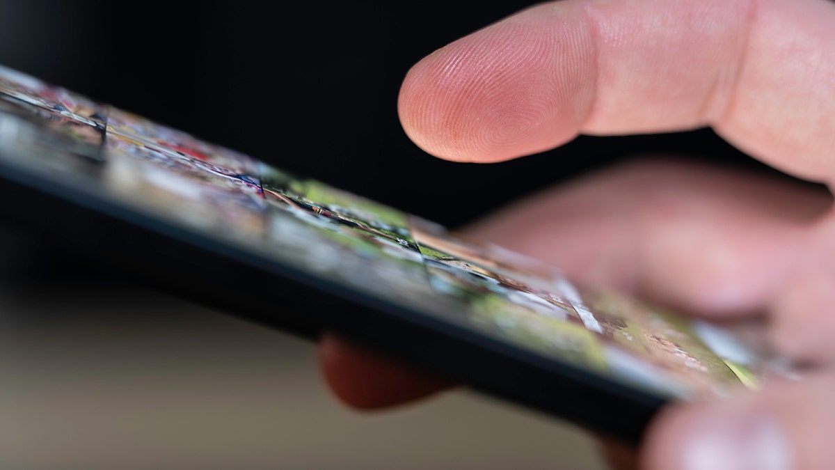 Person using smartphone holding deceptive tracking link message.