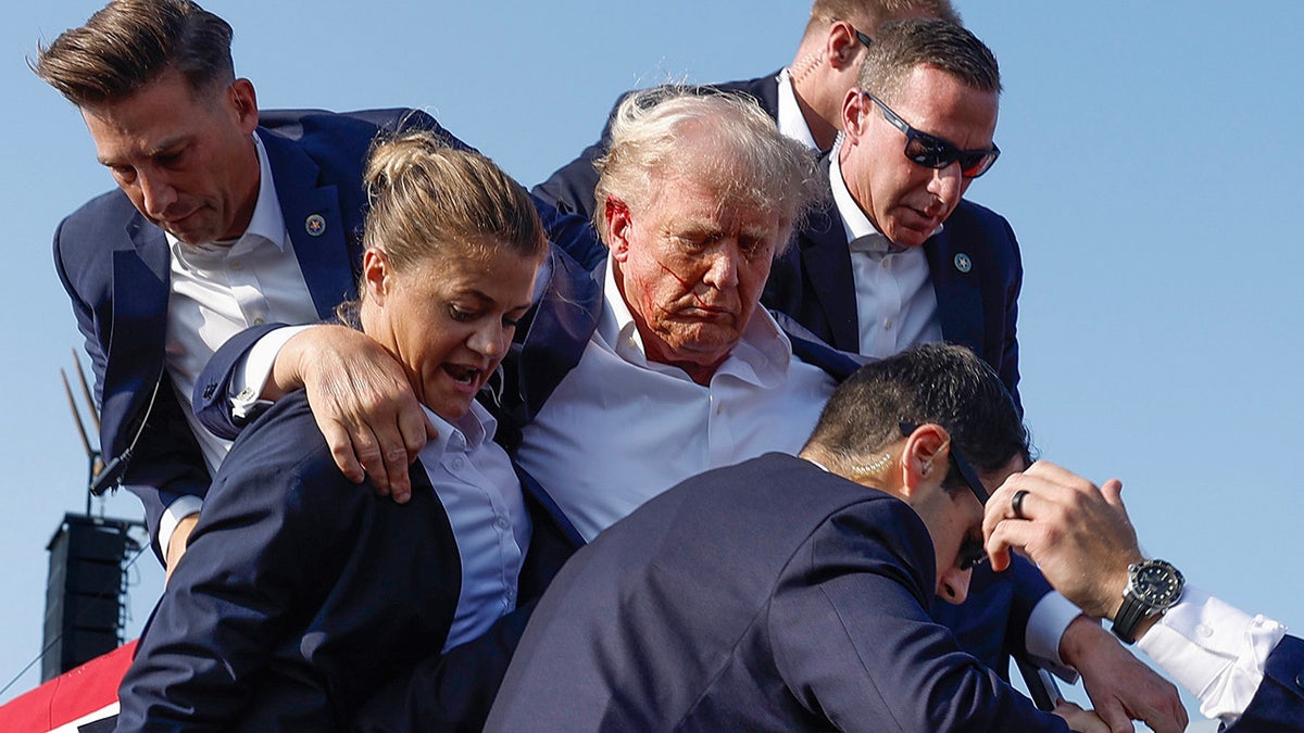 Donald Trump being rushed offstage by U.S. Secret Service agents at a rally