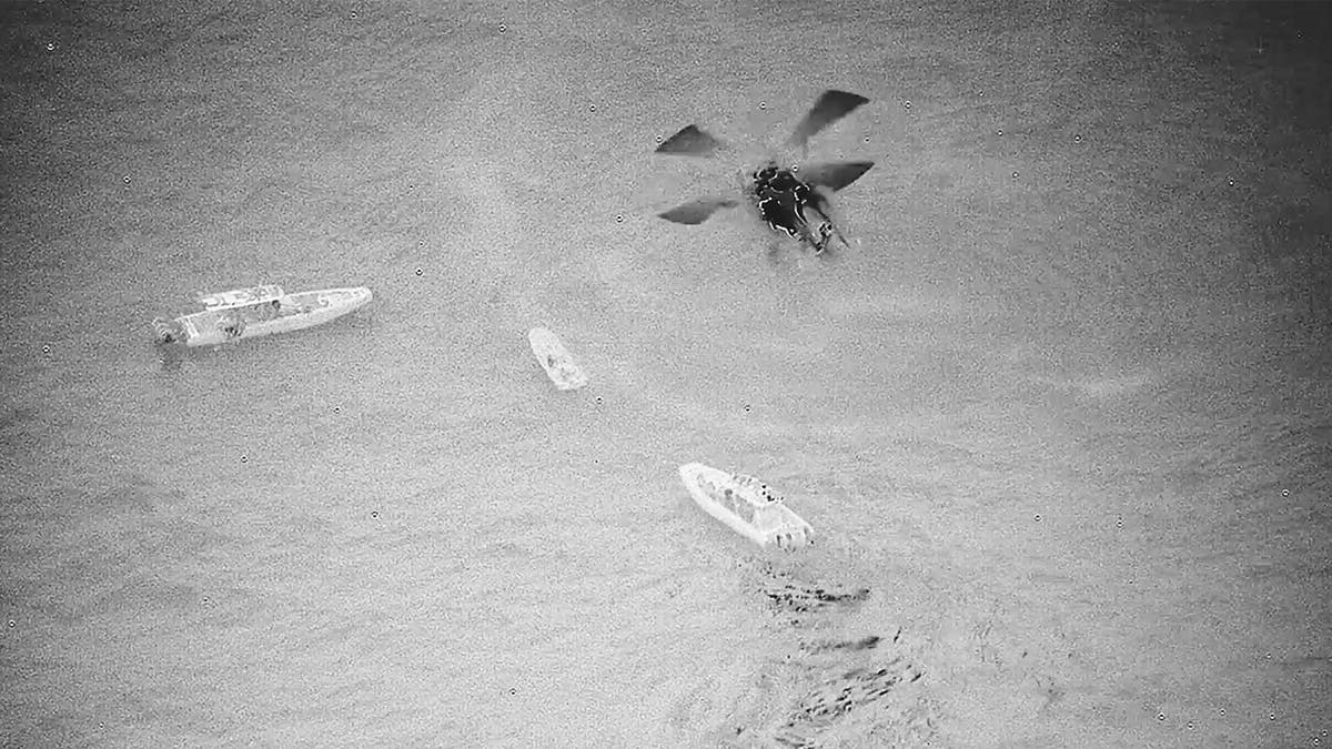 A helicopter hovers a set of three boats
