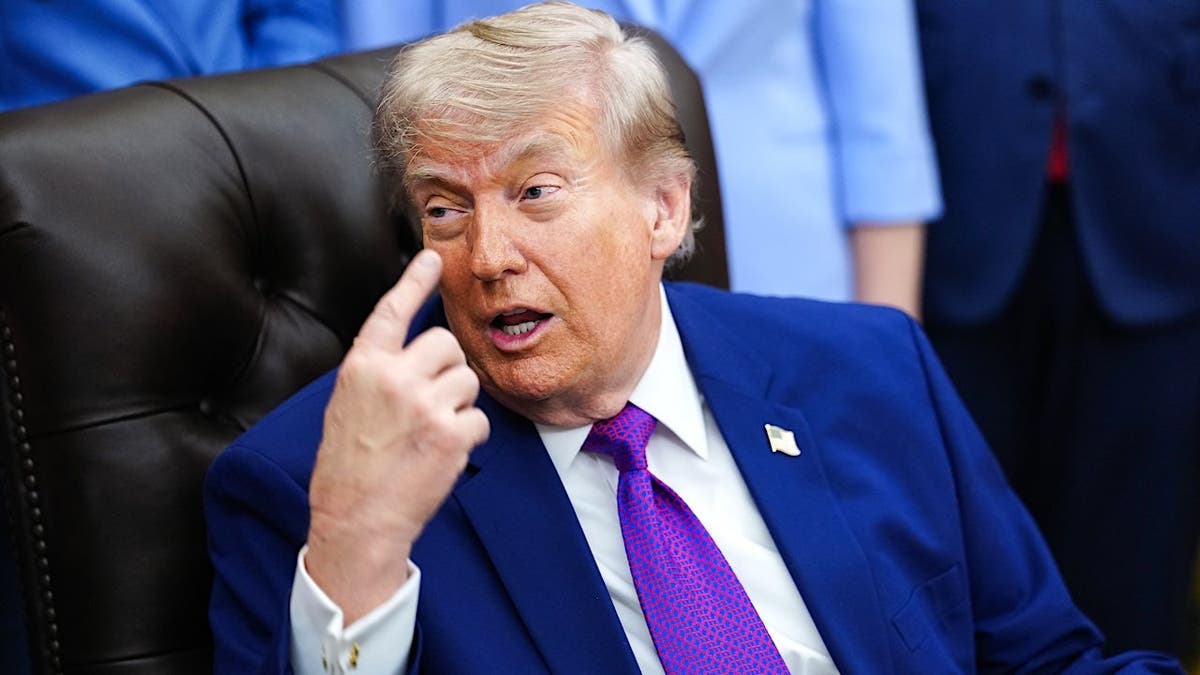 President Donald Trump points to his brain in the Oval Office