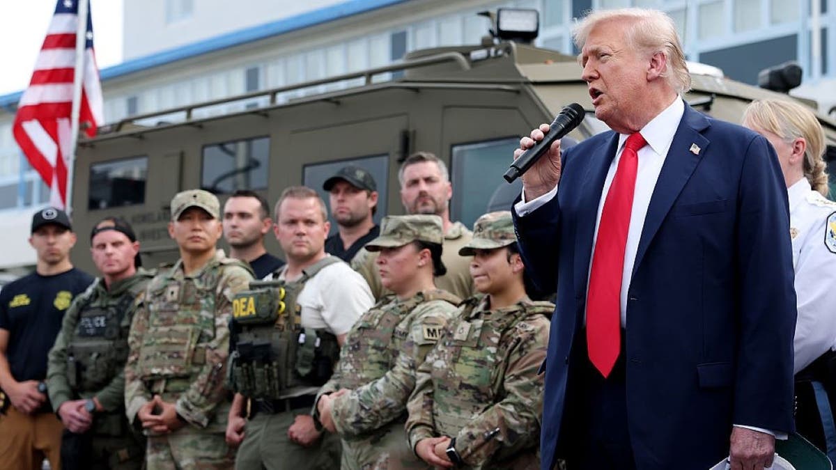 President Donald Trump standing with federal law enforcement officers at a police facility