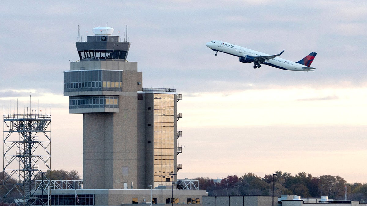 A Delta Air Lines plane taking off with air traffic control tower in background at Minneapolis–Saint Paul International Airport