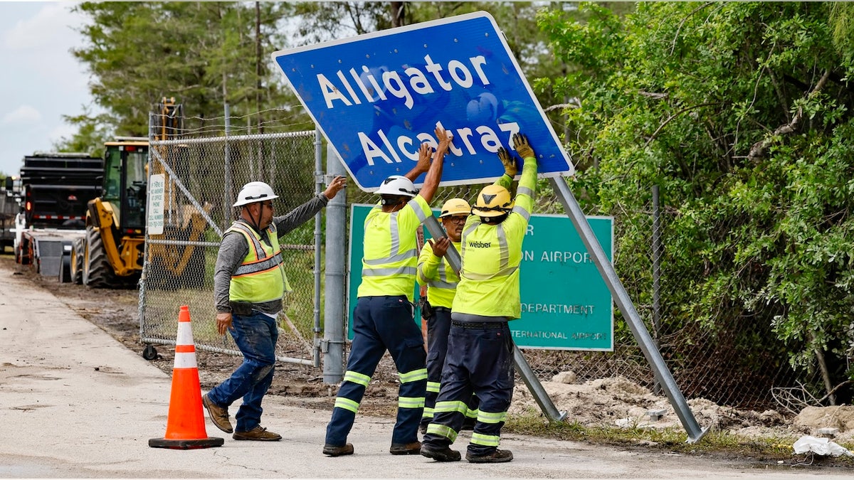 Workers installing a permanent Alligator Alcatraz sign in the Florida Everglades