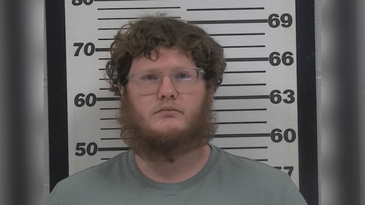 Man with facial hair posing in a mugshot