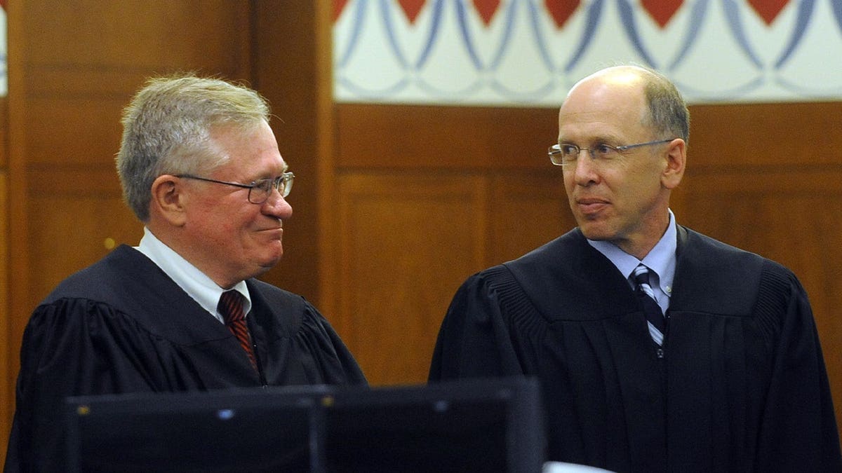 two judges wearing black smile at each other
