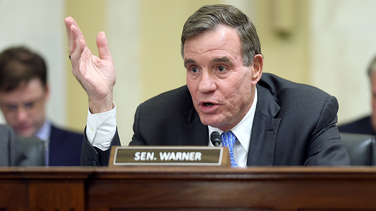 Sen. Mark Warner raising his palm during a Senate hearing in Washington