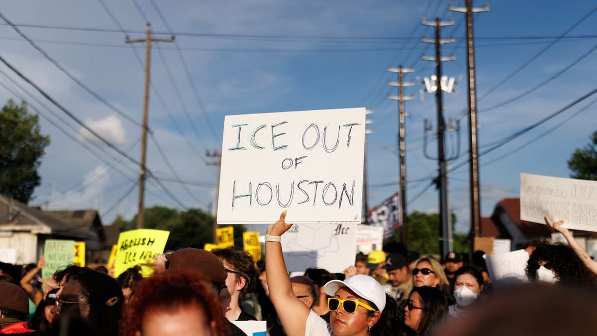 A woman holds a sign reading 
