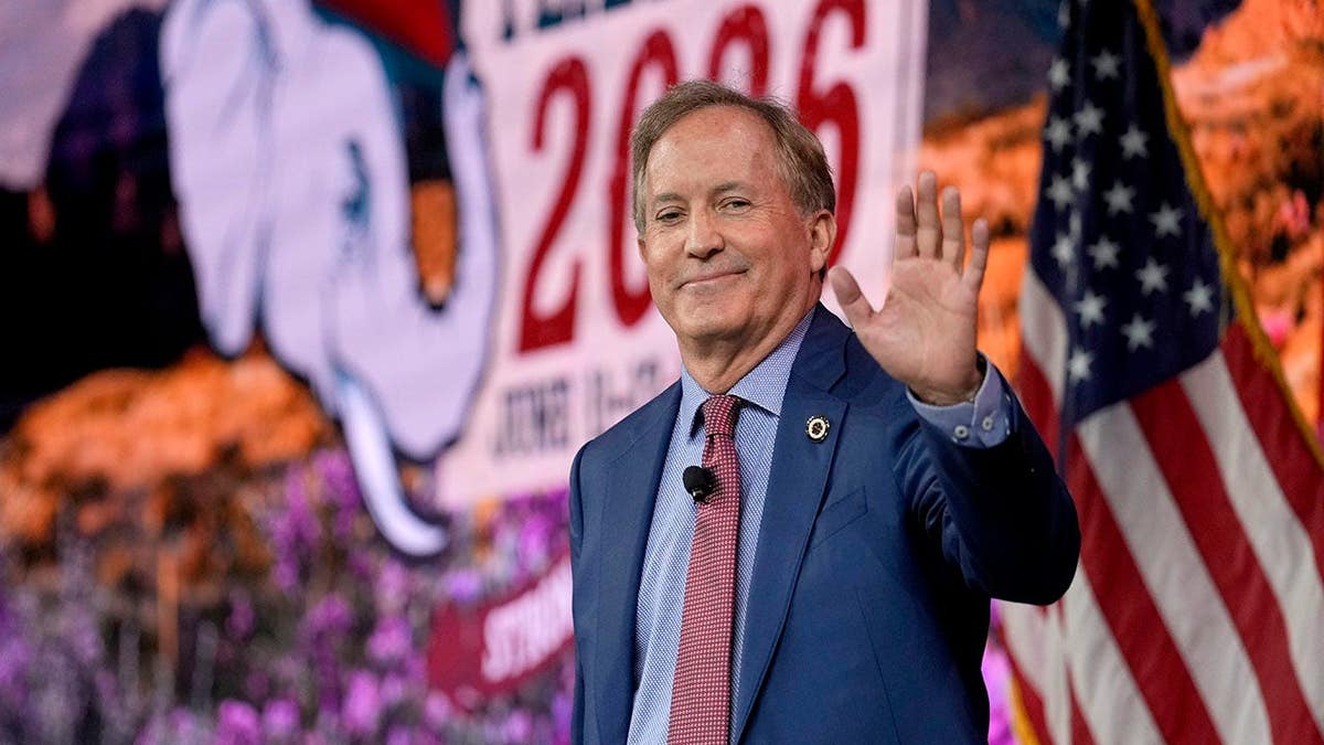 Ken Paxton smiles and waves