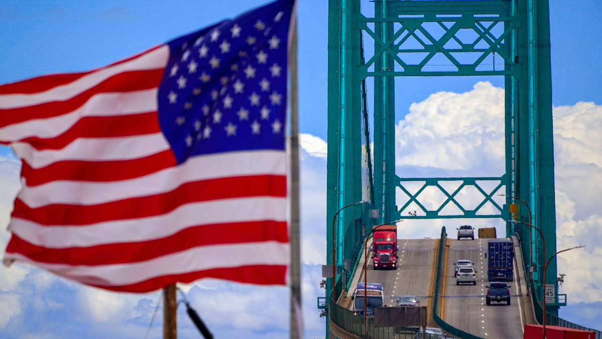 Trucks and cars are seen on the Vincent Thomas Bridge as steady winds blow a U.S. flag.