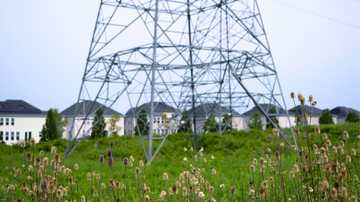 A transmission tower is shown adjacent to single-family homes with nearby data center infrastructure.