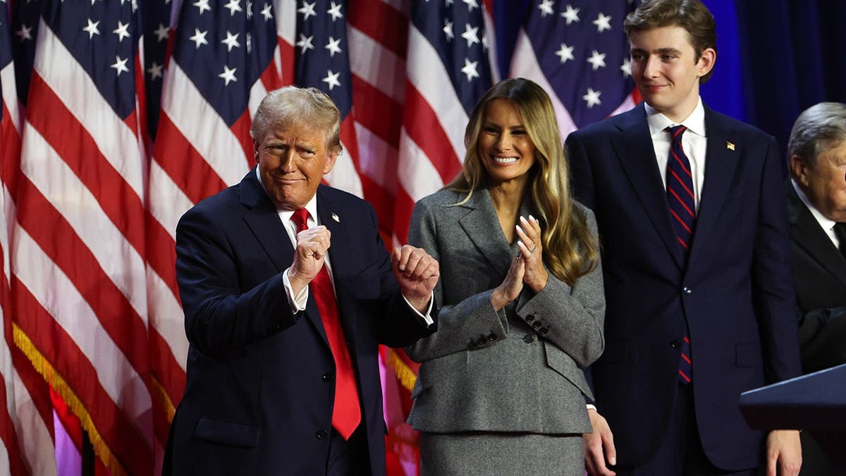 Donald Trump dancing on stage with Melania Trump and Barron Trump at an event