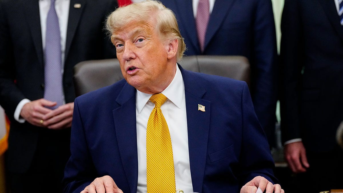 Donald Trump talks to the media as his advisors stand behind him