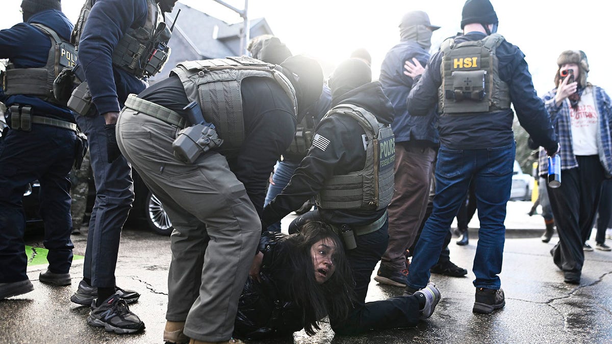 ICE agents detain a woman after pulling her from a car before on January 13, 2026, in Minneapolis, Minnesota. The Trump administration has deployed over 2,400 Department of Homeland Security agents to the state of Minnesota in a push to apprehend undocumented immigrants.