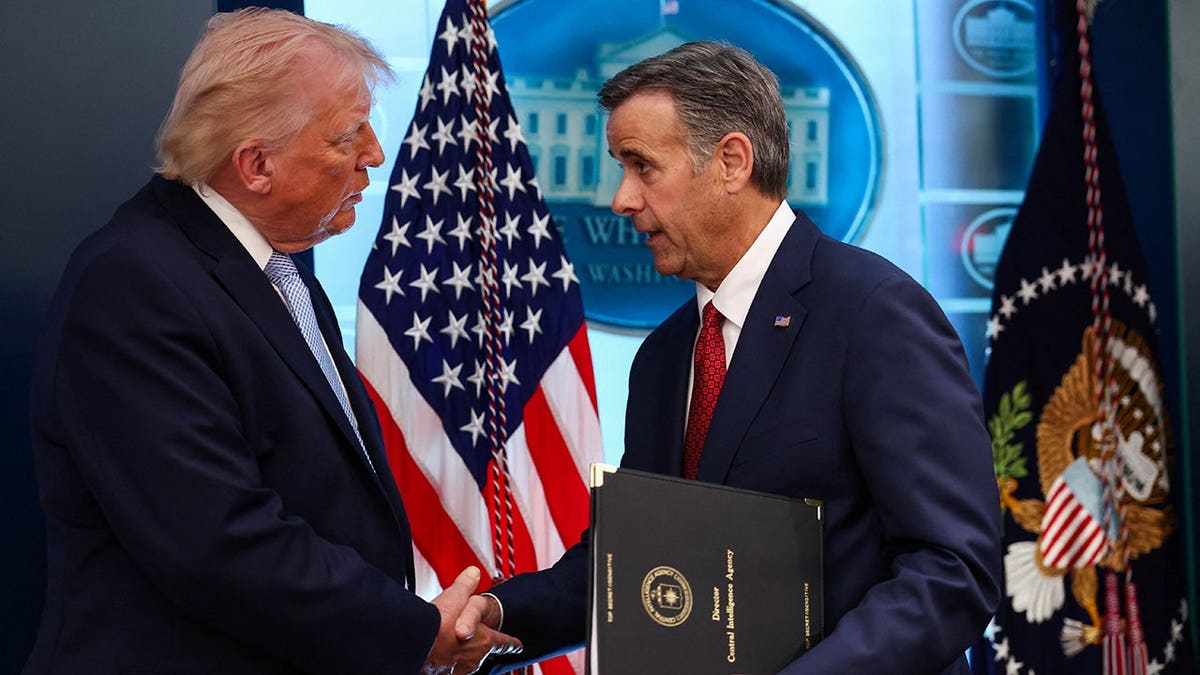 Donald Trump shakes hands with CIA Director John Ratcliffe in the White House briefing room.