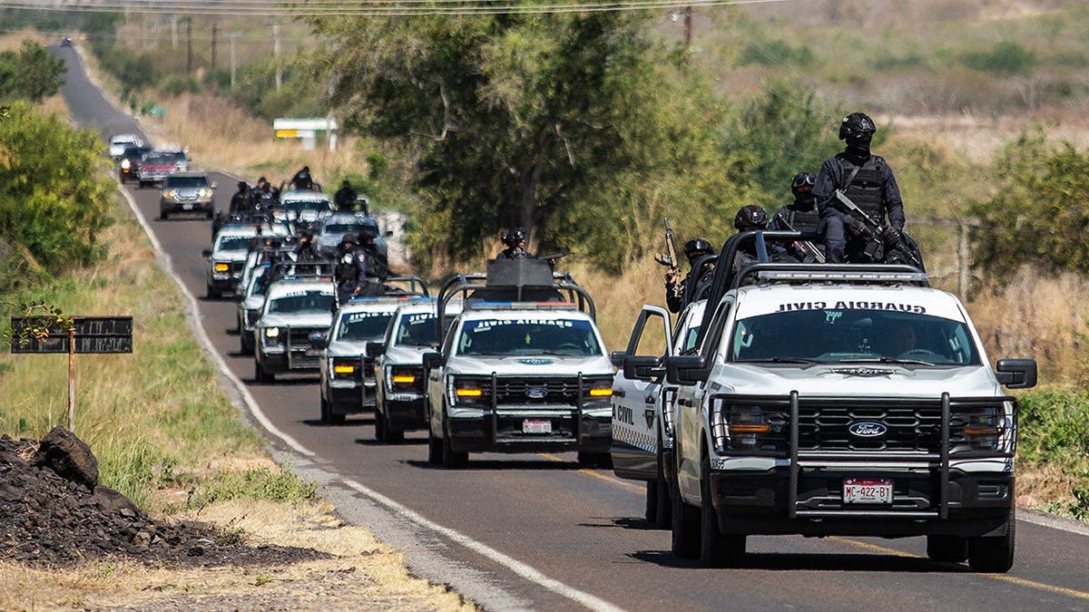 Civil Guard of Michoacan members patrol a highway with armored vehicles.