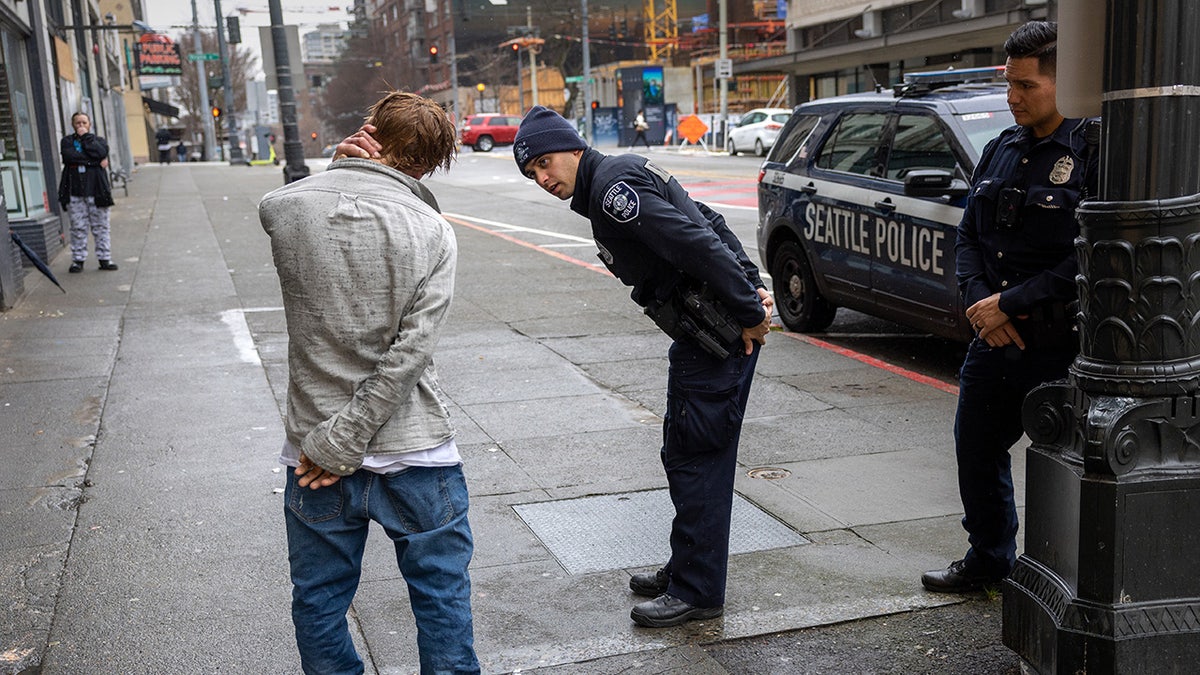 Police officers check on a man who said he has been smoking fentanyl in downtown Seattle on March 14, 2022 in Seattle, Washington. Use of the powerful opioid has surged in the last several years, especially in Seattle's large homeless community.