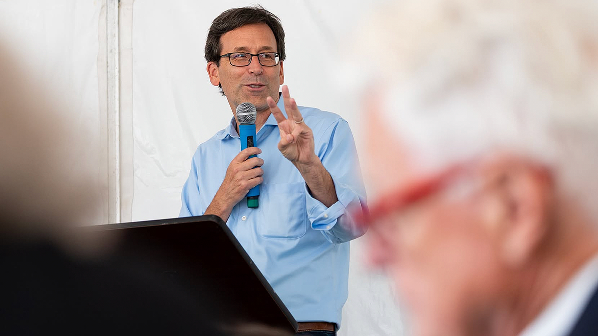Washington Gov. Bob Ferguson speaks into a handheld microphone from a podium