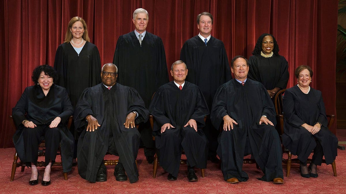 Supreme Court justices pose for a group photo, seated and standing in rows.