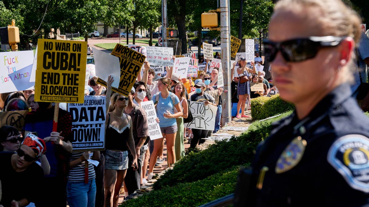 Demonstrators protest against AI and data centers as a police officer looks on in Chapel Hill.
