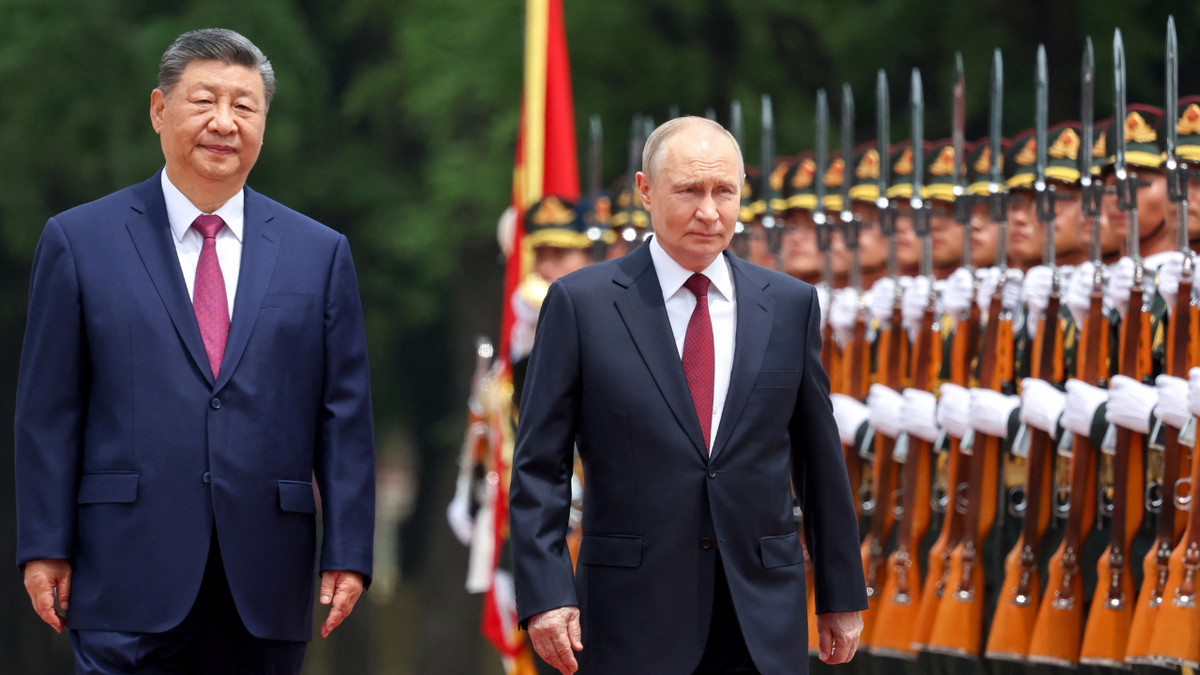Pool photograph distributed by the Russian state agency Sputnik, Russia's President Vladimir Putin (C) and China's President Xi Jinping (L) inspect a honor guard during a welcome ceremony at the Great Hall of the People in Beijing on May 20, 2026.