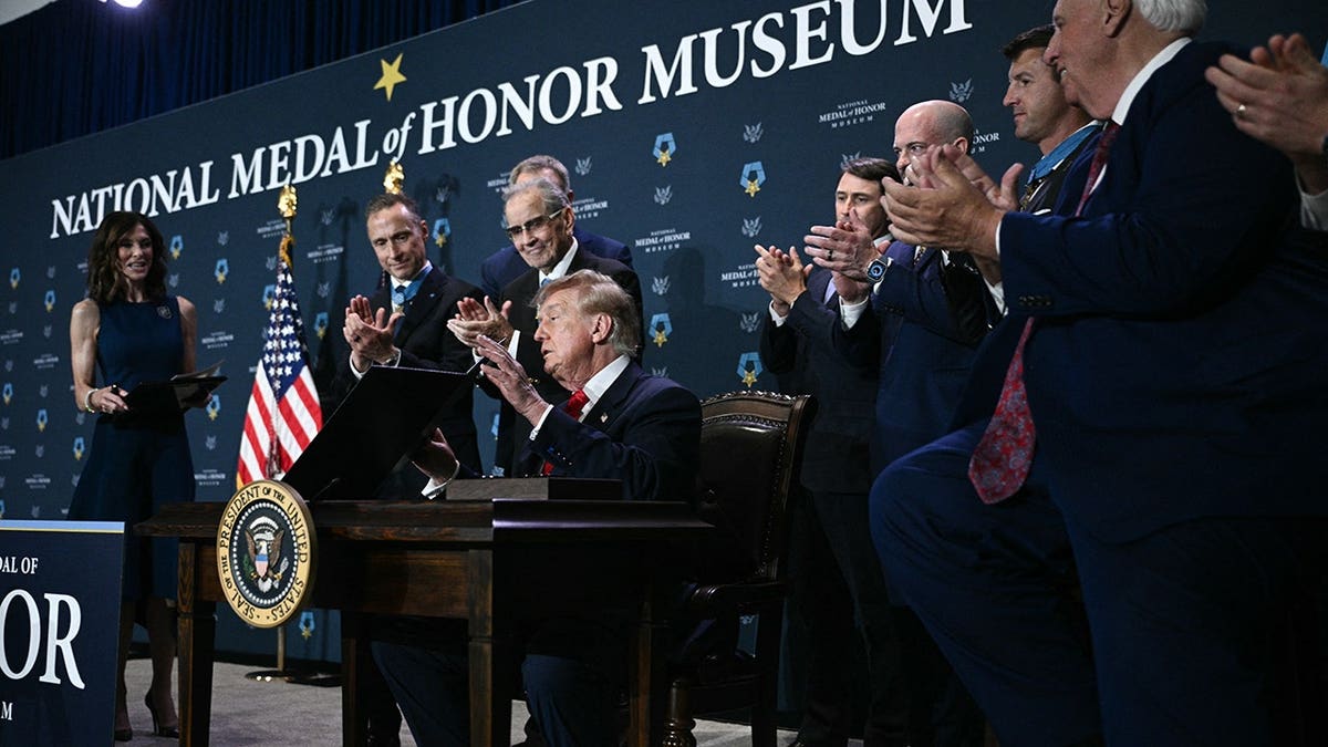 Donald Trump signs a document at a table in Arlington, Texas.